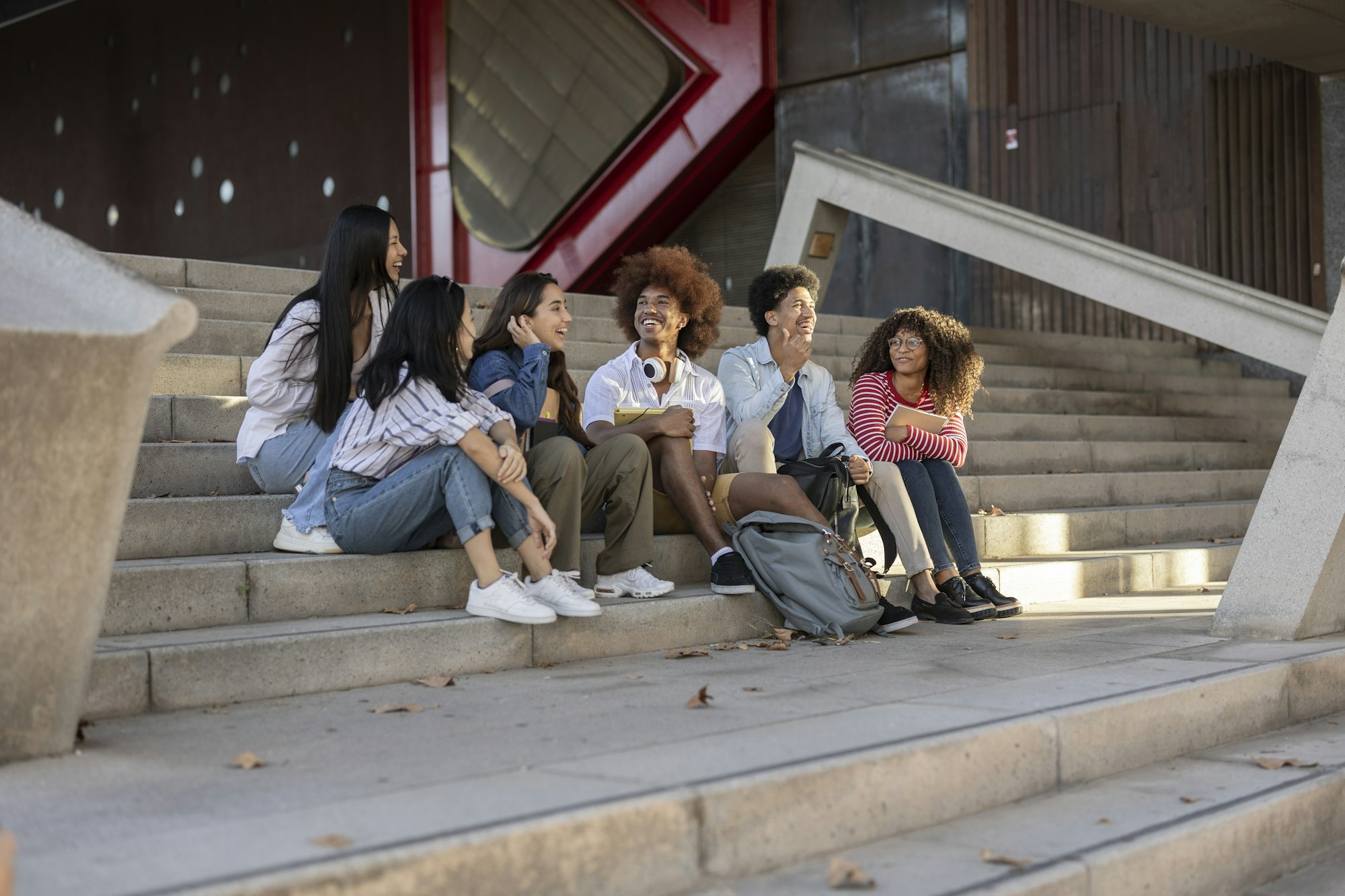 Group of multiracial students talking and sitting on the stairs of the university.